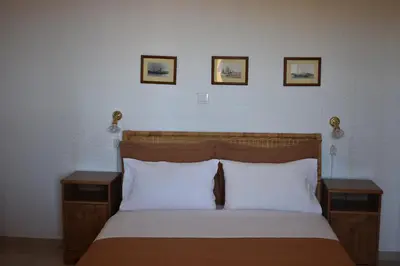 a bedroom with a bed with two night stands and three pictures on the wall at Eriketi Studios in Agia Marina Aegina