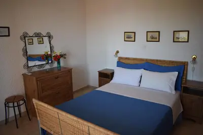 a bedroom with a blue and white bed and a dresser at Eriketi Studios in Agia Marina Aegina