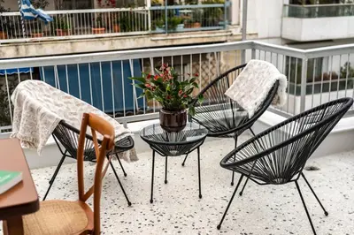 three chairs and a table with a potted plant on a balcony at Acropolis Horizon by WeHost Athens in Athens