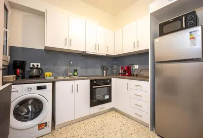 a kitchen with white cabinets and a washer and dryer at Acropolis Horizon by WeHost Athens in Athens