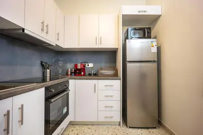 a kitchen with white cabinets and a stainless steel refrigerator at Acropolis Horizon by WeHost Athens in Athens