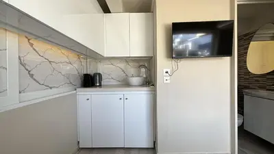 a kitchen with white cabinets and a tv on the wall at Mania's Studio by Lycabetus in Athens