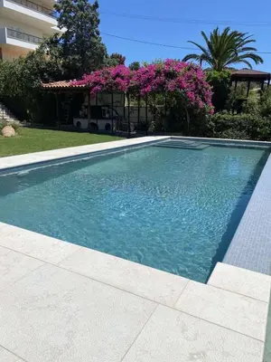 a swimming pool in a yard with pink flowers at Villa Leonidas in Anavissos