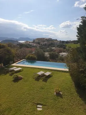 a swimming pool in a yard with a grassy field at Villa Leonidas in Anavissos