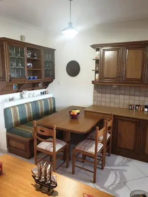 a kitchen with a wooden table and chairs and a counter at Villa Leonidas in Anavissos