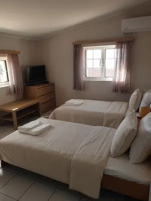 a hotel room with two beds and a television at Villa Leonidas in Anavissos