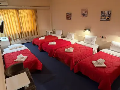 a hotel room with four beds with red sheets at Cavo D' Oro in Piraeus