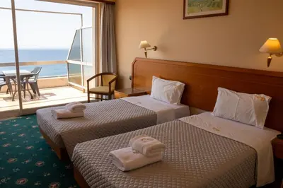 two beds in a hotel room with a view of the ocean at Cavo D' Oro in Piraeus