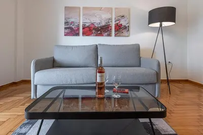 a living room with a couch and a bottle of wine on a table at Cozy Apartment with Office - 19min to Athens Center in Athens
