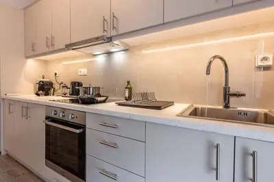a kitchen with white cabinets and a sink at Cozy Apartment with Office - 19min to Athens Center in Athens