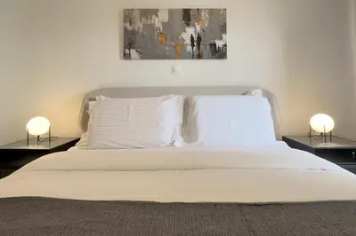 a bedroom with a bed with white sheets and two lamps at Cozy Apartment with Office - 19min to Athens Center in Athens