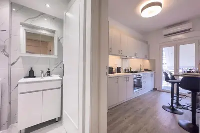 a kitchen with white cabinets and a table with chairs at Cozy Apartment with Office - 19min to Athens Center in Athens
