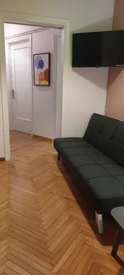 a living room with a black couch and a wooden floor at Rose Apartment Athens Center , 5BD, 2 BATH in Athens