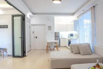 a living room with a white couch and a kitchen at Athens! Didems Hideaway! in Athens