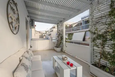 an apartment patio with a white couch and a table at Athens! Didems Hideaway! in Athens