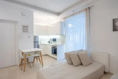 a white living room with a couch and a table at Athens! Didems Hideaway! in Athens