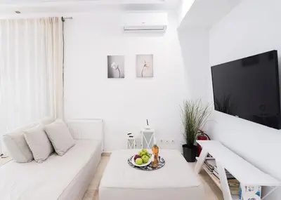 a white living room with a white couch and a tv at Athens! Didems Hideaway! in Athens