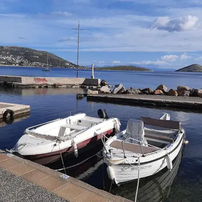 two boats are docked at a dock in the water at Andromeda-The Airport Home in Markopoulo