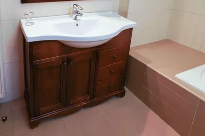 a bathroom with a white sink and a wooden cabinet at Marvelous apartment in Plaka in Athens