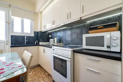 a kitchen with white cabinets and a microwave and a table at Piraiki Sea View Apt, 2bdrms, 4 pers by MPS in Piraeus
