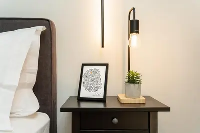 a nightstand with a picture on it next to a bed at Stylish 1BD Apt in Elliniko in Athens