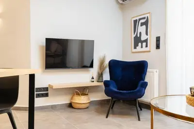 a living room with a blue chair and a tv at Stylish 1BD Apt in Elliniko in Athens