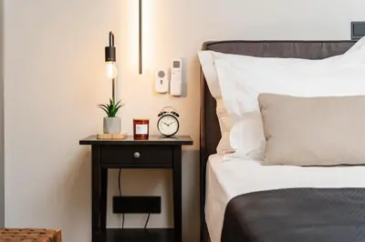 a bed with a side table with a clock on it at Stylish 1BD Apt in Elliniko in Athens