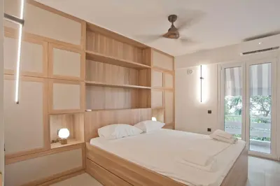 a bedroom with a large white bed with wooden shelves at Asteria studio in Glyfada in Athens