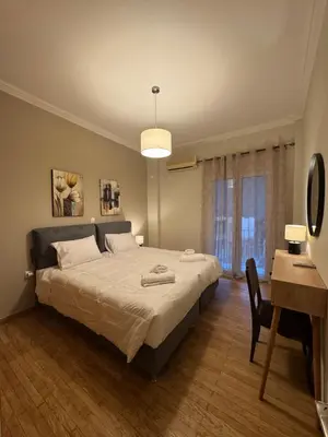 a bedroom with a large bed with a desk and a table at Nelly's Athens Apartments in Athens