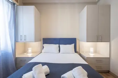 a bedroom with a bed with white cabinets and towels at Kastella Waves Chic 2-Bedroom Getaway in Piraeus