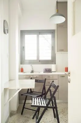 a white kitchen with a table and a chair at Cosy Penthhouse with stunning view in Athens
