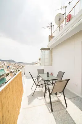 a patio with a table and chairs on a roof at Cosy Penthhouse with stunning view in Athens