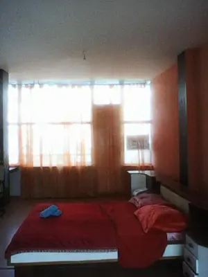 a bedroom with a bed with red sheets and two windows at Duffy Duck apartment athens in Athens