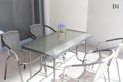 a glass table with chairs and a vase with purple flowers at Waylink Residences - Marina Floisvou - Z4 in Athens
