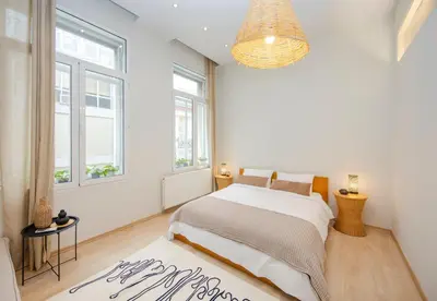 a white bedroom with a bed and a large window at K8 Syntagma in Athens