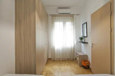 a bedroom with a bed and a window and a wooden door at Bellissimo Ctr Stylish Reno 2BR Apt near Acropolis in Athens