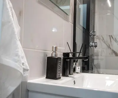 a bathroom sink with a black soap dispenser on it at Stephan's Modern Apartment in Athens