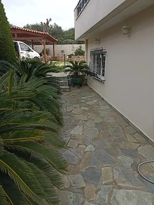 a stone walkway in front of a house at Cosy garden house in a villa in Palaiá Fókaia