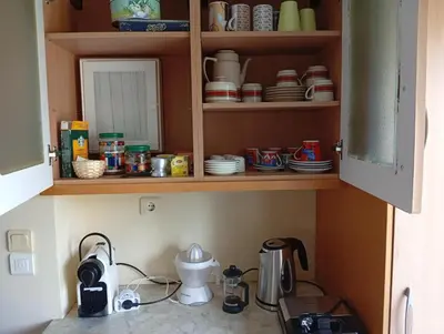 a kitchen with a cupboard filled with dishes at Cosy garden house in a villa in Palaiá Fókaia