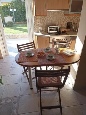 a kitchen with a wooden table with chairs and a table and a table at Cosy garden house in a villa in Palaiá Fókaia