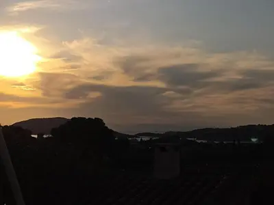 a view of the sunset from the roof of a house at Cosy garden house in a villa in Palaiá Fókaia