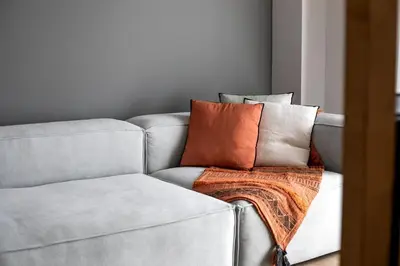 a gray couch with an orange blanket on it at Brisk - Chic 1 Bedroom Apartment in Athens in Athens