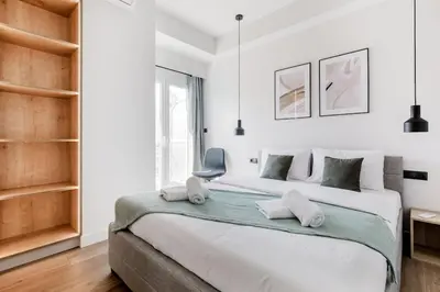 a white bedroom with a large bed and a chair at Brisk - Chic 1 Bedroom Apartment in Athens in Athens