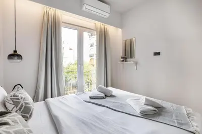 a white bedroom with a bed and a window at Bask - Glamorous 2 Bedroom Apartment in Athens in Athens