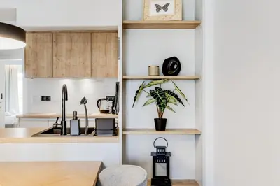a kitchen with white walls and wooden shelves at Bask - Glamorous 2 Bedroom Apartment in Athens in Athens