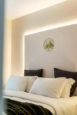 a bed with white pillows and a clock on the wall at Elegant Aphrodite, 2 Bedroom Apartment, by Acropolin in Athens