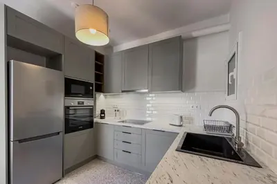 a kitchen with white cabinets and a stainless steel refrigerator at Phaedrus Living Koukaki Verdant Marble in Athens