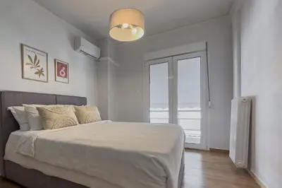 a white bedroom with a bed and a large window at Phaedrus Living Koukaki Verdant Marble in Athens