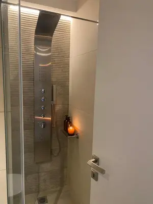 a bathroom with a shower with a candle in it at New Modern 2BD aprt with shared rooftop pool B2 in Athens