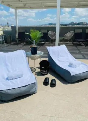 two beds and a table and chairs on a patio at New Modern 2BD aprt with shared rooftop pool B2 in Athens